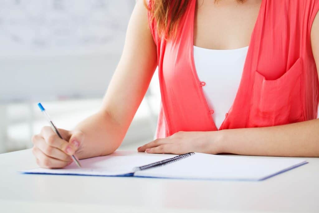 A female student is writing in her notebook inside the classroom.