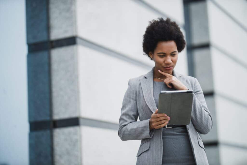 A female employee is outside the office building holding her tablet.