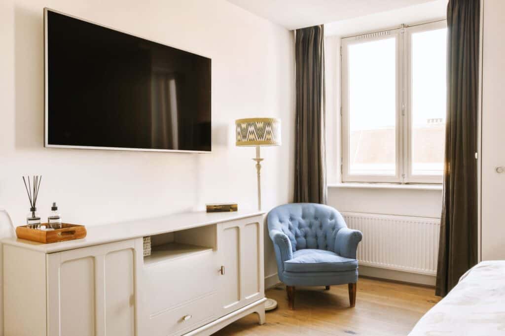 A bedroom with flat screen TV and blue chair
