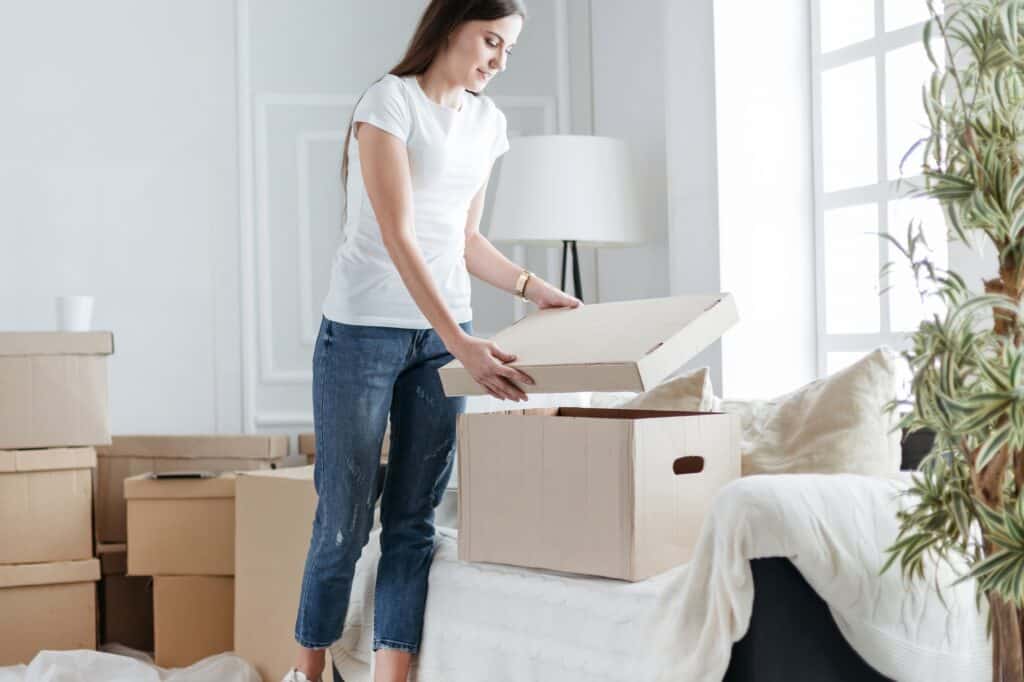 A young lady is opening a box upon arrival at her new apartment