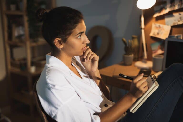 A young woman is thinking what to write on the house-move checklist in the concept of 'How to Create a Moving Checklist for Your Move to Finchley'.
