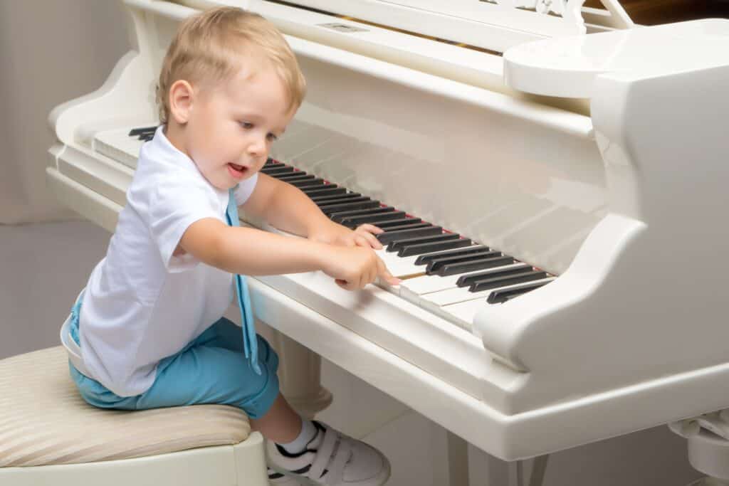 A little boy playing the piano in the concept of 'How to Move Pianos and Other Large Fragile Objects When Moving'.