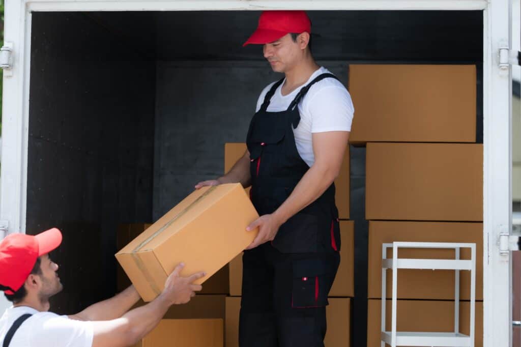 Two movers at the back of the moving truck unloading the boxes